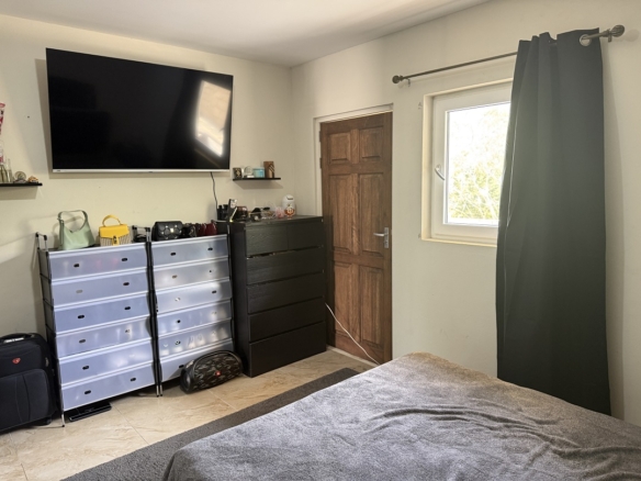 Bedroom with television, storage furniture, and window in the Alto Vista 26 W apartment.