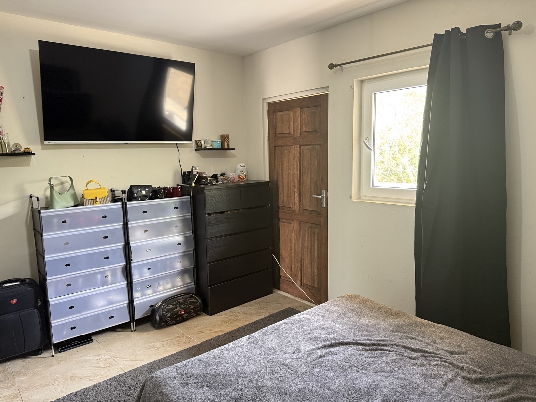 Bedroom with television, storage furniture, and window in the Alto Vista 26 W apartment.