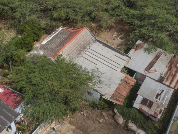 Aerial photograph showing an existing property surrounded by vegetation and neighboring structures.