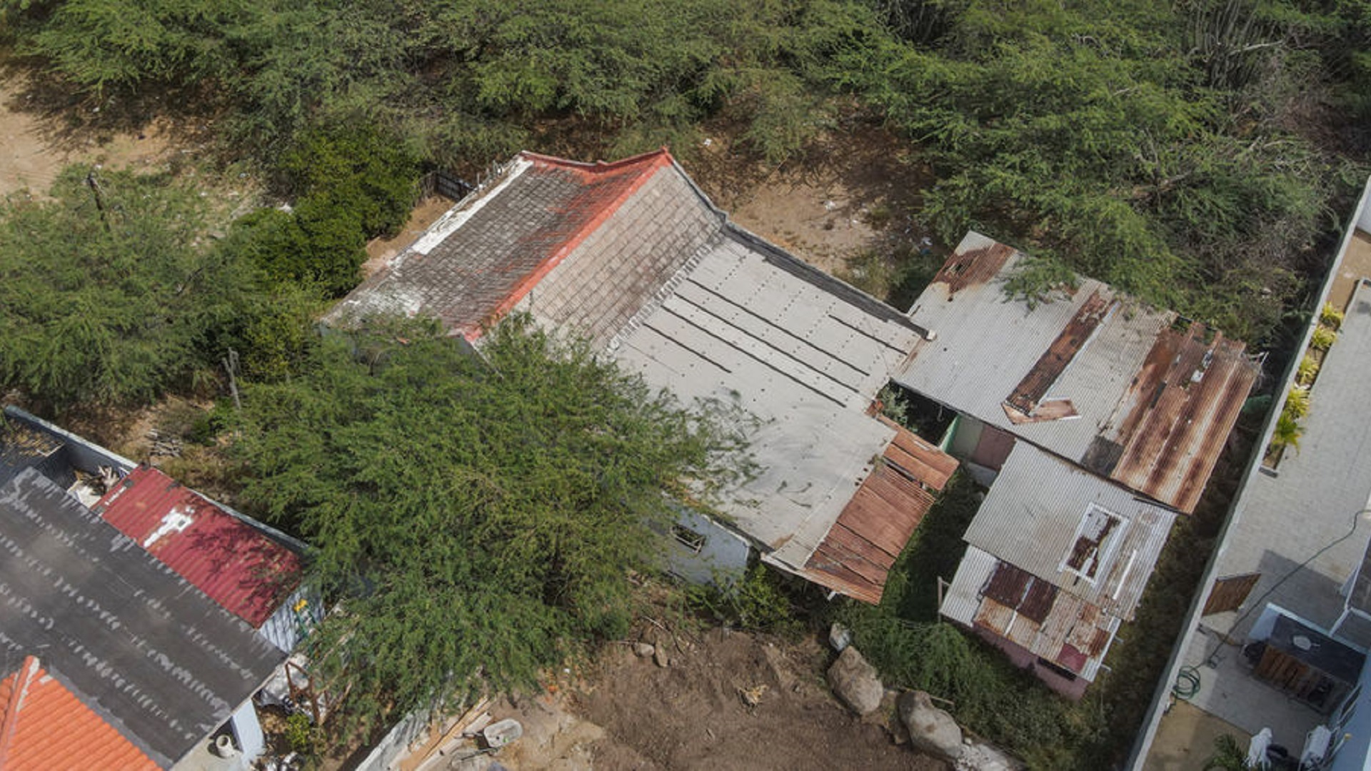 Aerial photograph showing an existing property surrounded by vegetation and neighboring structures.
