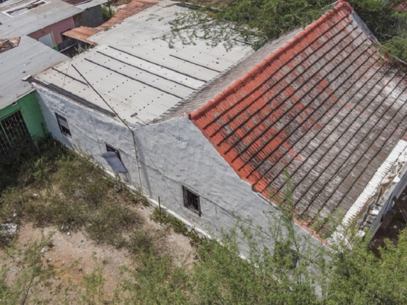 Drone image of an existing building with multiple roof sections and surrounding vegetation.