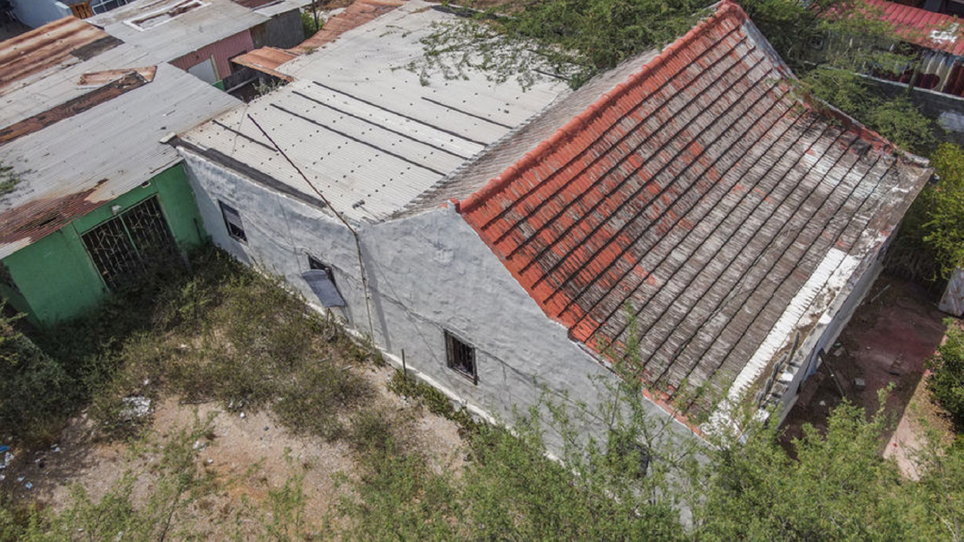 Drone image of an existing building with multiple roof sections and surrounding vegetation.