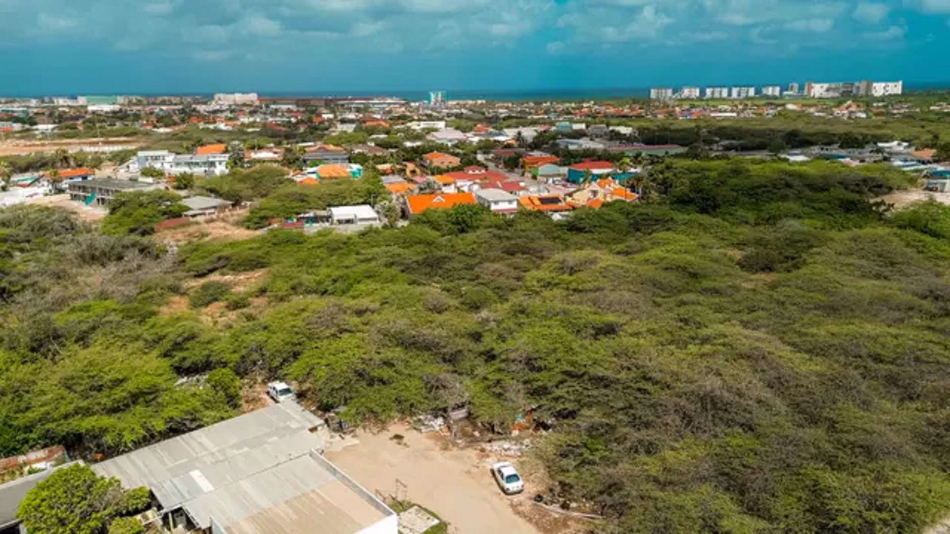 bubali-development-land-coastal-skyline-view-noord-aruba-real-estate-for-sale Aerial view of development land in Bubali, Noord, Aruba, with surrounding residential areas and a distant coastal skyline.