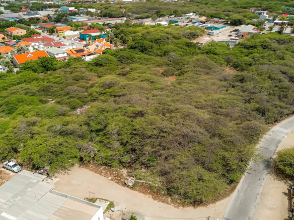 Corner aerial view of development land in Bubali, Noord, Aruba, showing adjacent roads and nearby residential buildings.