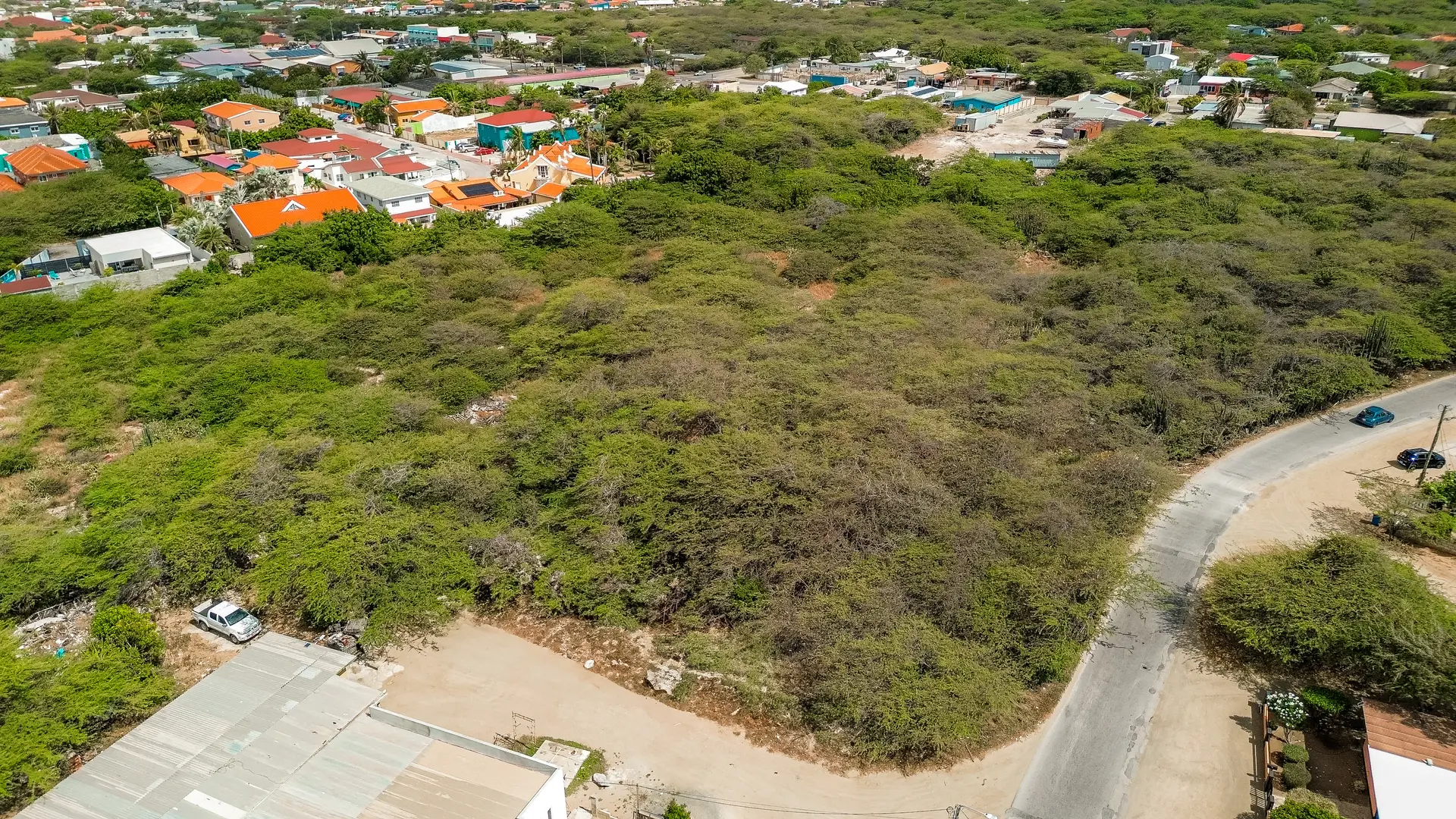 Corner aerial view of development land in Bubali, Noord, Aruba, showing adjacent roads and nearby residential buildings.