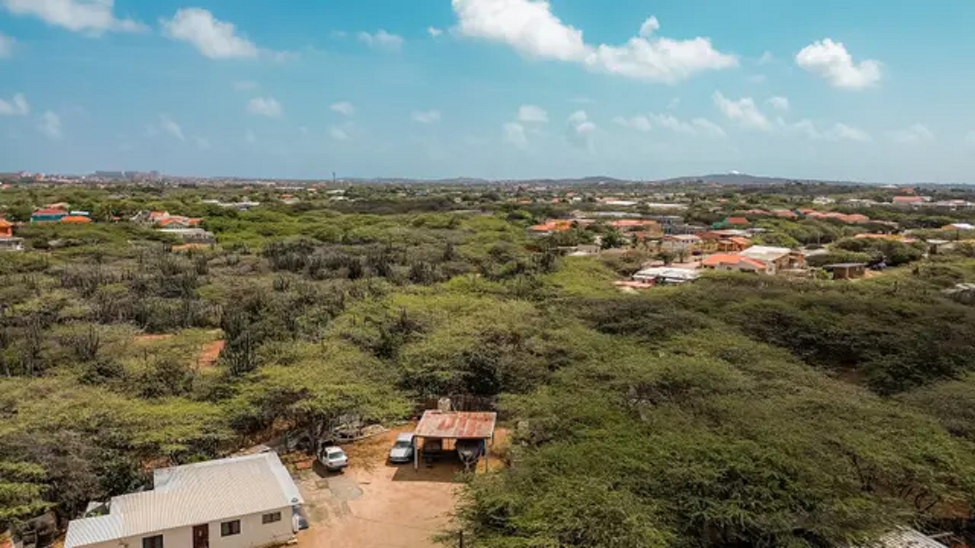 Broad aerial landscape view of development land for sale in Bubali, Noord, Aruba, with neighboring homes and natural vegetation throughout the area.