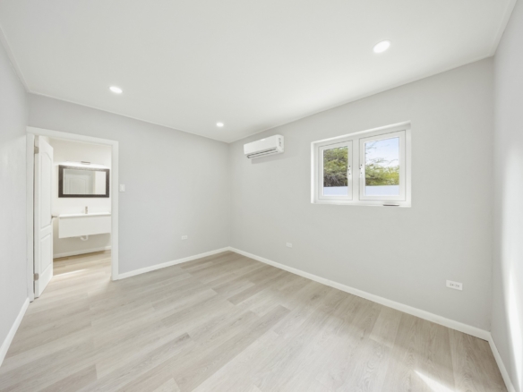 Bright bedroom with light flooring, split air-conditioning unit, and ensuite bathroom access at Pos Abao 10 F in Noord, Aruba.