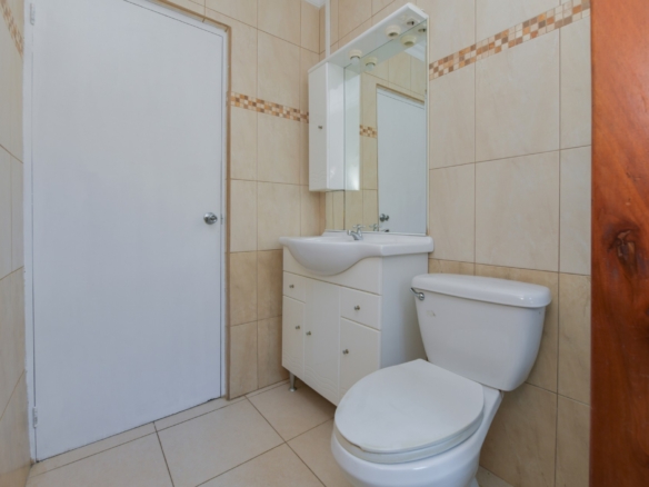 Bathroom vanity with sink, mirror cabinet, and toilet in a clean tiled bathroom in Aruba.