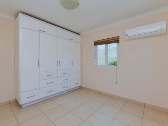 Bedroom with large built-in wardrobe, air conditioning, and window in Tanki Leendert Aruba.