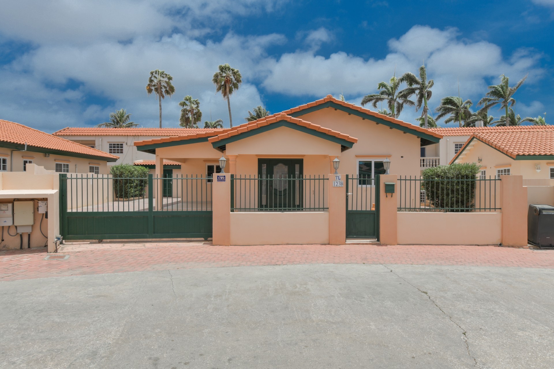 Front view of a 3-bedroom home for sale in Tanki Leendert Aruba with gated entrance, covered porch, and landscaped surroundings.