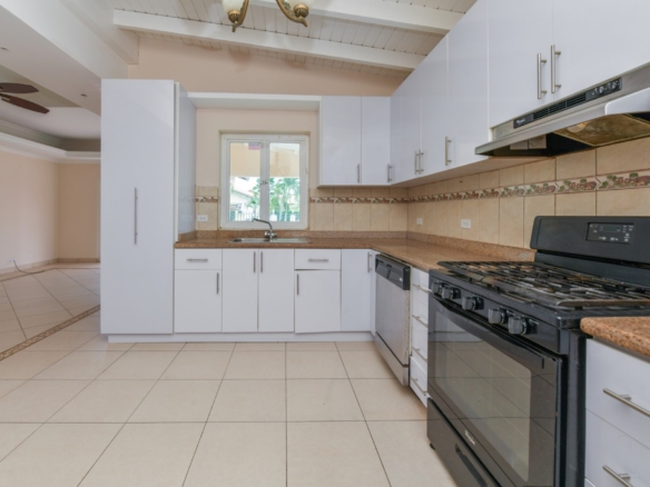 Kitchen with granite countertops, gas stove, dishwasher, and window overlooking the outdoor area.