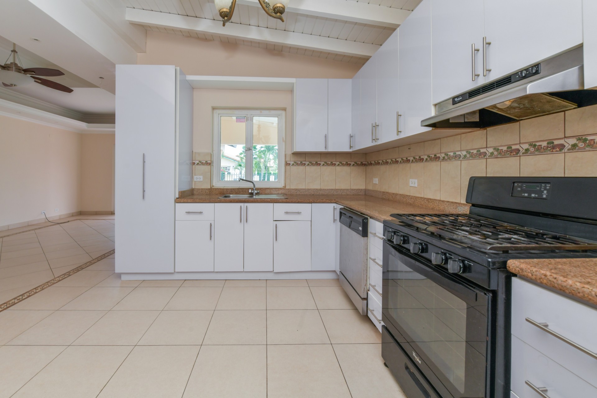 Kitchen with granite countertops, gas stove, dishwasher, and window overlooking the outdoor area.