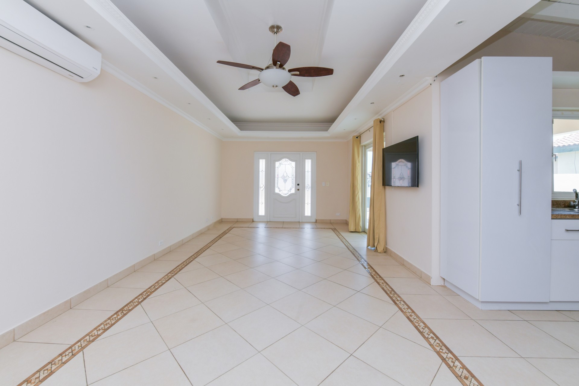 Bright living room with decorative ceiling details, tiled flooring, and natural light in Tanki Leendert Aruba.