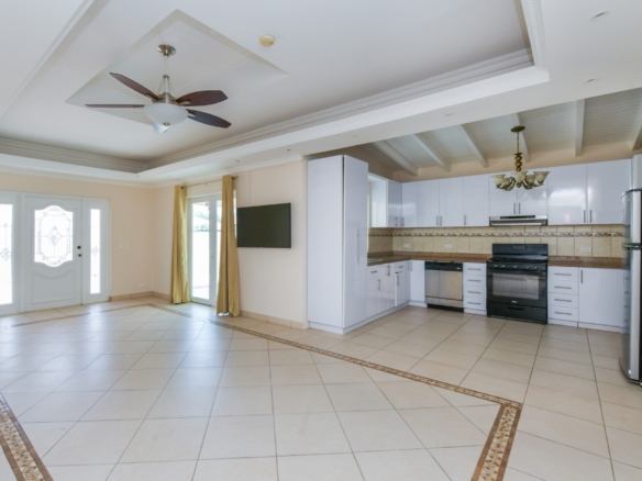 Open-concept living room and kitchen with tiled floors, high ceilings, and modern cabinetry in Aruba.