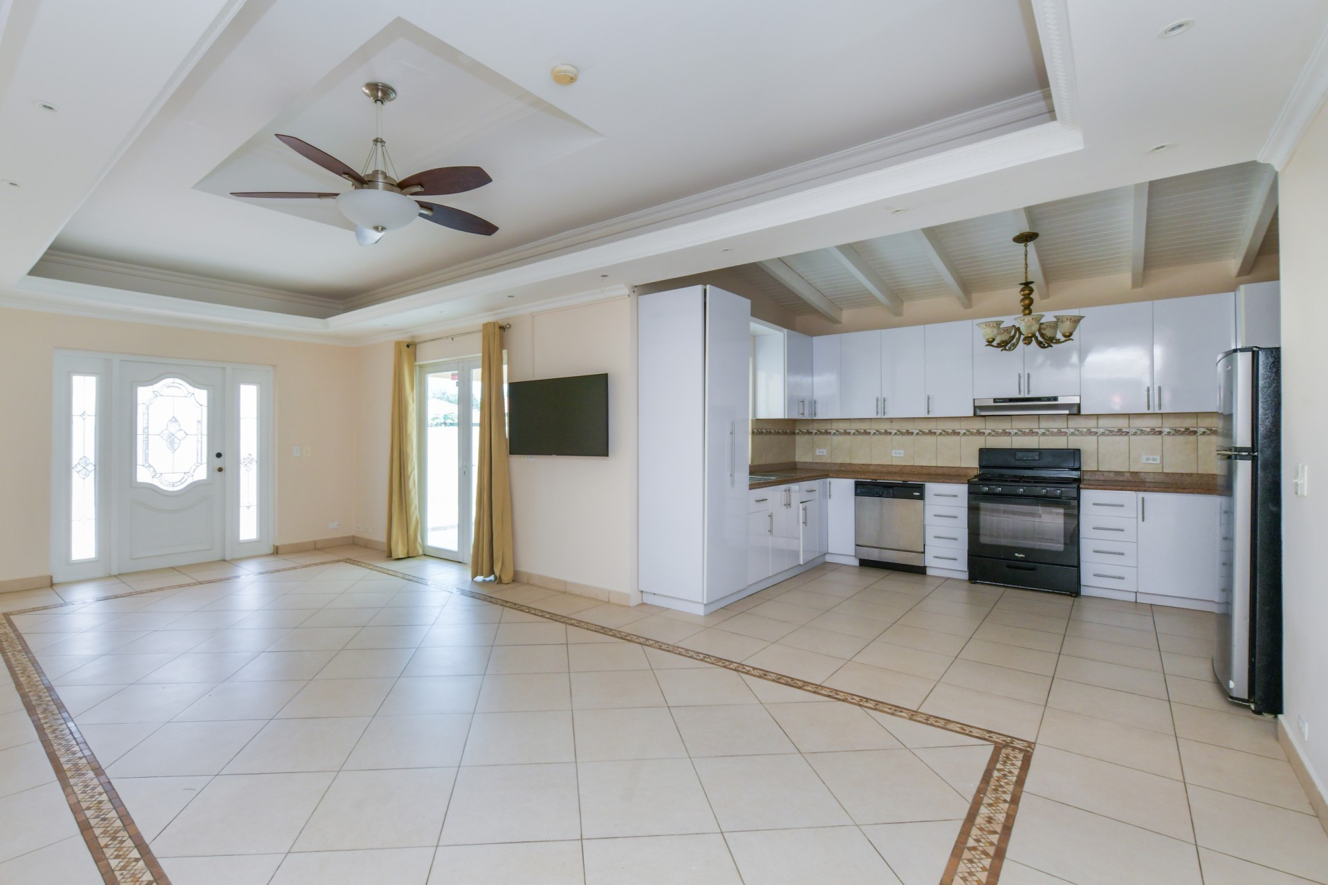 Open-concept living room and kitchen with tiled floors, high ceilings, and modern cabinetry in Aruba.