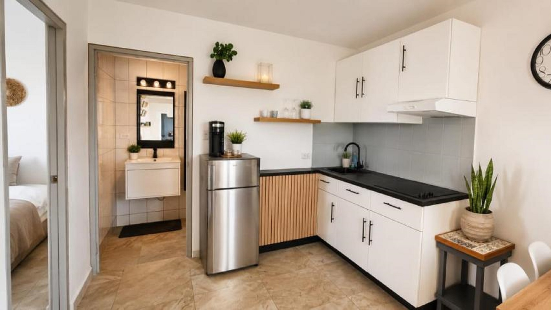 Compact kitchen in an Aruba vacation rental with white cabinets, a refrigerator, open shelving, and a sink.