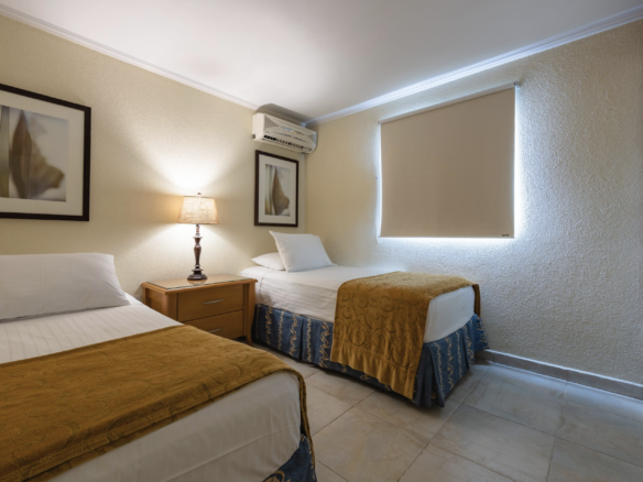 Furnished twin bedroom with two separate beds at Marquee Apartments in Noord, Aruba.