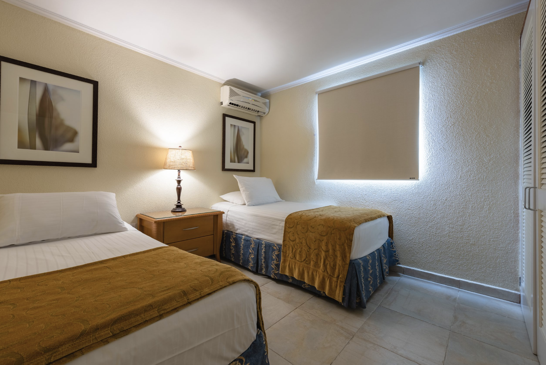 Furnished twin bedroom with two separate beds at Marquee Apartments in Noord, Aruba.